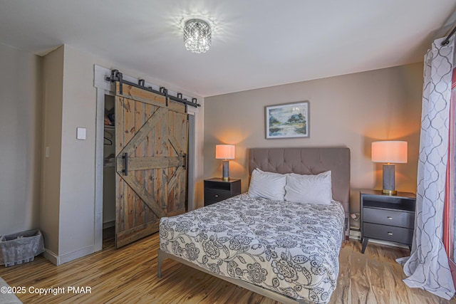 bedroom with wood-type flooring and a barn door