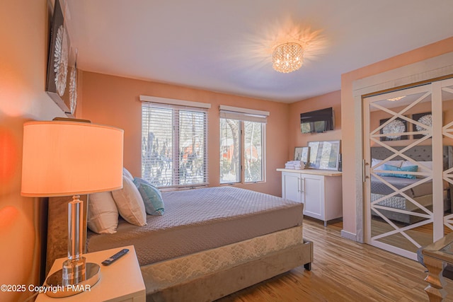 bedroom featuring an inviting chandelier and light wood-type flooring