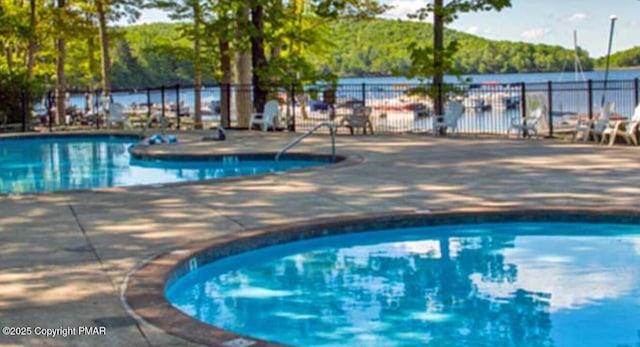 view of swimming pool featuring a patio and a water view