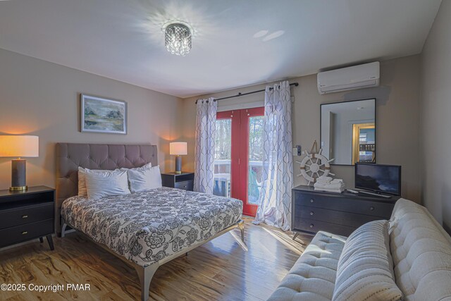 bedroom with wood-type flooring, access to exterior, and a wall unit AC