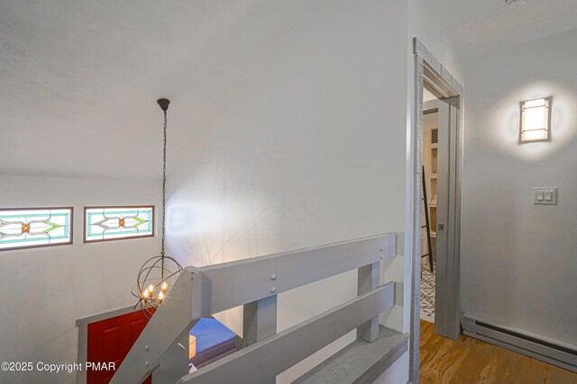 hallway featuring light hardwood / wood-style floors, a chandelier, and baseboard heating