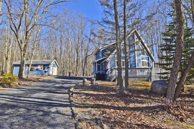 view of side of home with gravel driveway and a deck