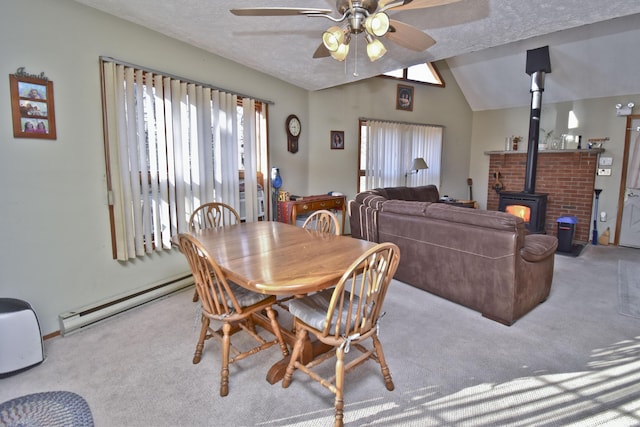 dining room with vaulted ceiling, baseboard heating, a wood stove, a textured ceiling, and a ceiling fan