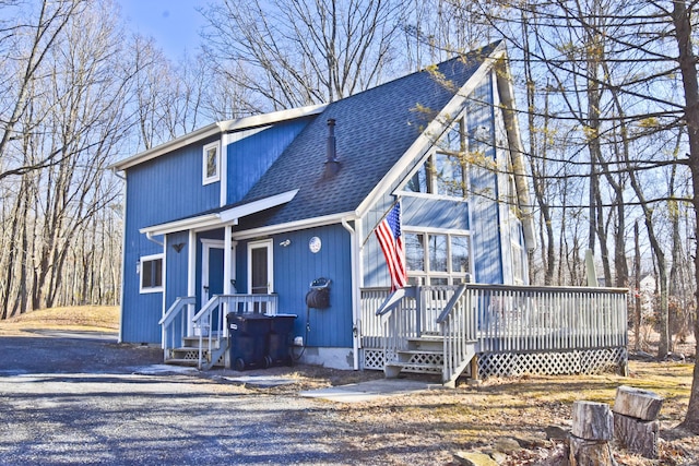 chalet / cabin with a shingled roof and a deck