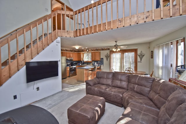 living room featuring stairs, concrete flooring, a towering ceiling, and ceiling fan