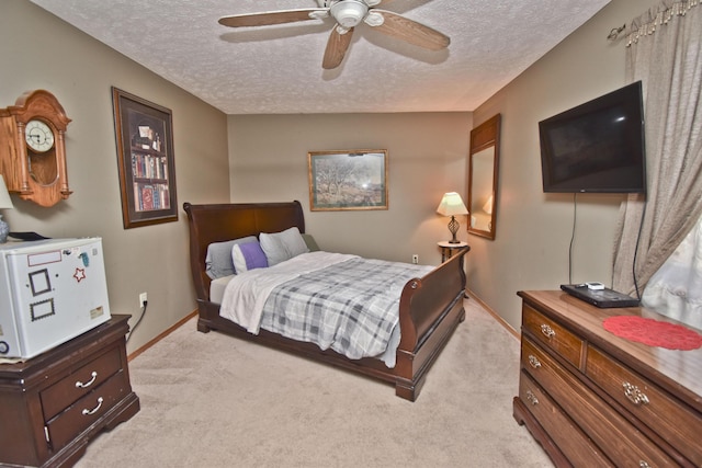 bedroom featuring baseboards, light colored carpet, a ceiling fan, and a textured ceiling