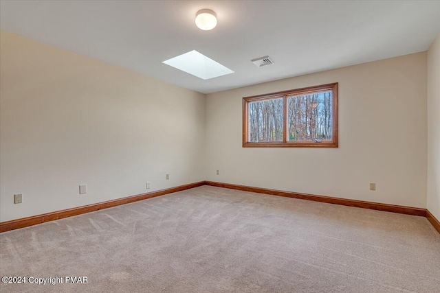 carpeted empty room with a skylight, visible vents, and baseboards