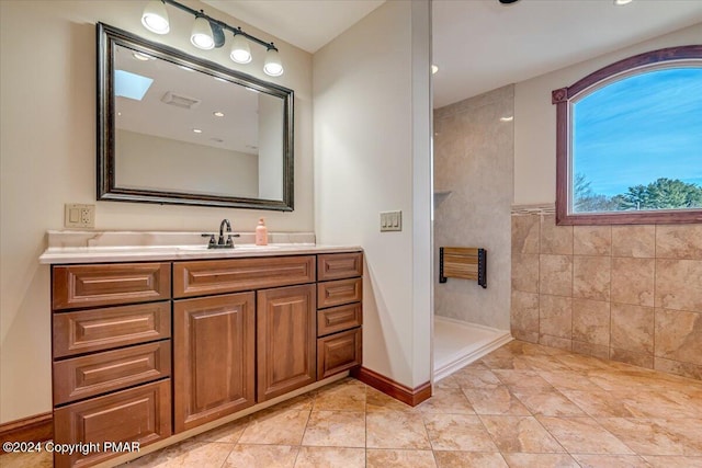 full bathroom featuring a walk in shower, vanity, and tile walls