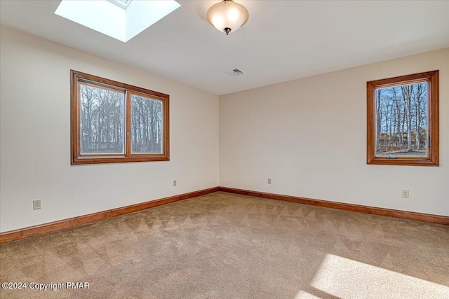 carpeted empty room with a skylight, visible vents, and baseboards