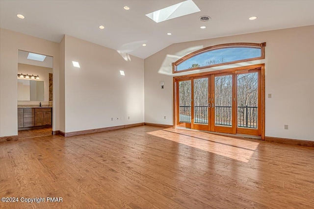 interior space featuring lofted ceiling with skylight, wood finished floors, visible vents, and baseboards