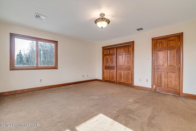 unfurnished bedroom with a closet, carpet, visible vents, and baseboards