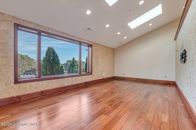 unfurnished room with light wood-style flooring, a skylight, visible vents, and wallpapered walls