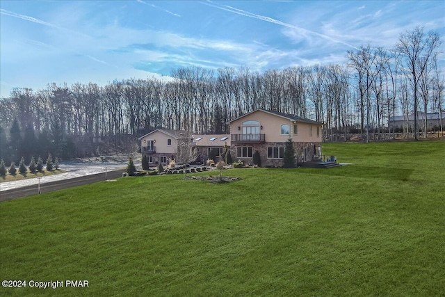 exterior space with driveway, a balcony, stucco siding, and a yard