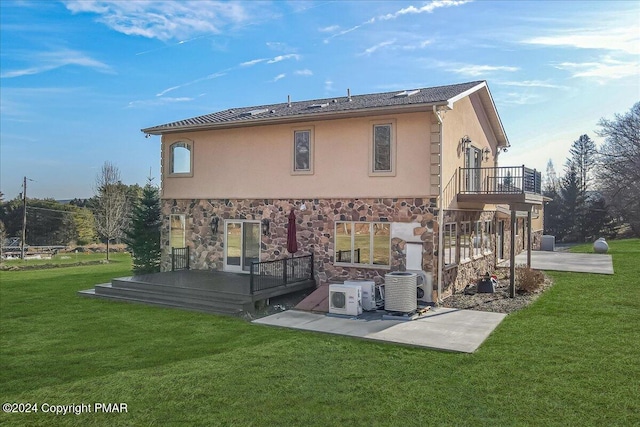 back of property with stone siding, a yard, a deck, and stucco siding