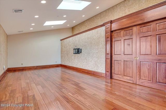 unfurnished room with recessed lighting, a skylight, visible vents, baseboards, and light wood-type flooring