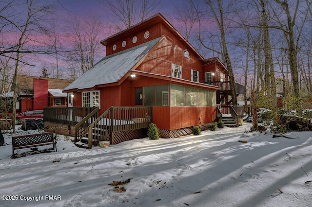 chalet / cabin with a sunroom, a shingled roof, and a wooden deck