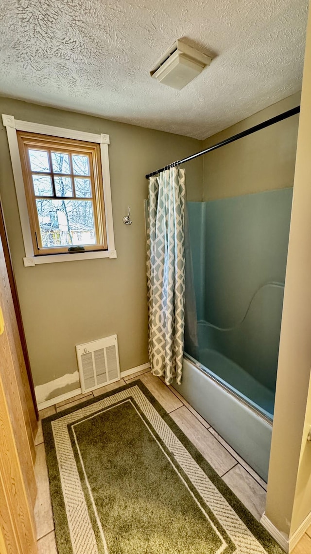 bathroom with shower / tub combo with curtain, baseboards, a textured ceiling, and visible vents