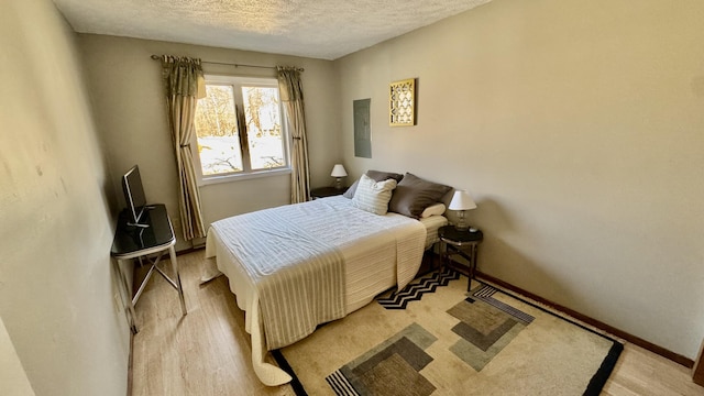 bedroom featuring a textured ceiling, baseboards, and light wood-style flooring