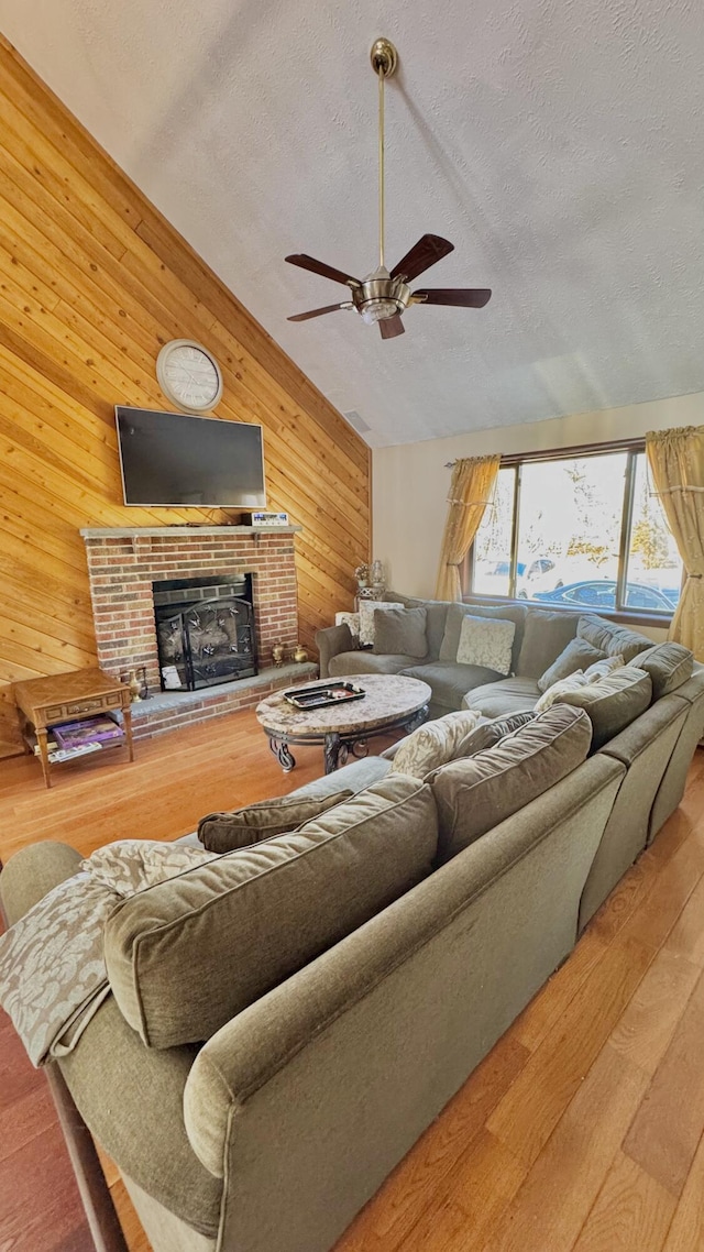 1905 Horseshoe Bnd, Tobyhanna, PA 18466 - living room featuring wooden walls, wood finished floors, ceiling fan, a brick fireplace, and a textured ceiling