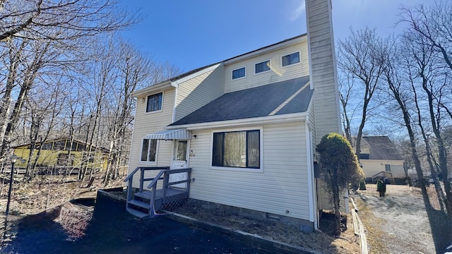back of property with roof with shingles and a chimney