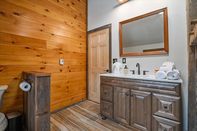 half bathroom with vanity, wood finish floors, and toilet