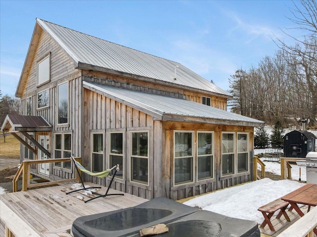 back of property featuring board and batten siding, a wooden deck, and metal roof