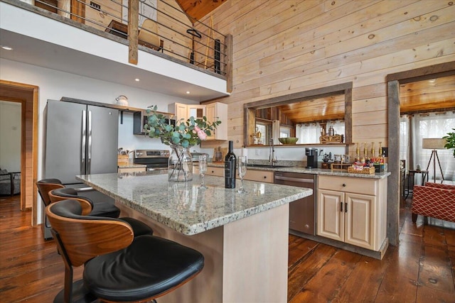 kitchen with a sink, light stone countertops, appliances with stainless steel finishes, and dark wood-style flooring