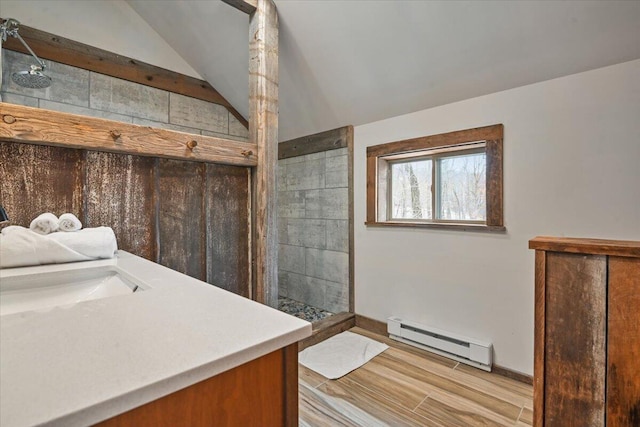 bathroom with a baseboard radiator, vanity, wood finished floors, tiled shower, and lofted ceiling