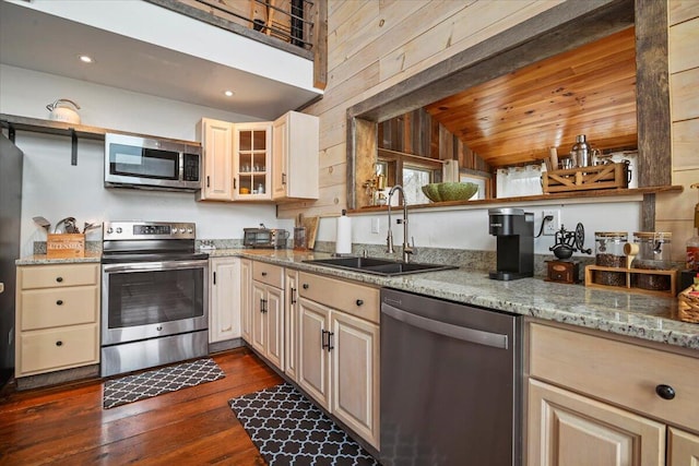kitchen with light stone counters, dark wood-type flooring, lofted ceiling, stainless steel appliances, and a sink