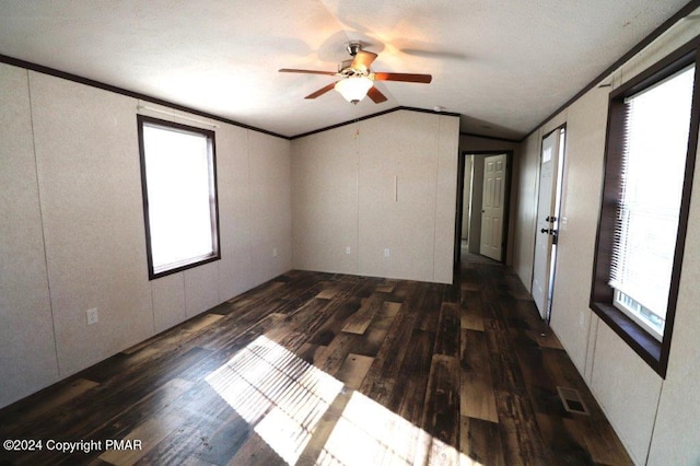 empty room with lofted ceiling, wood finished floors, a ceiling fan, visible vents, and crown molding