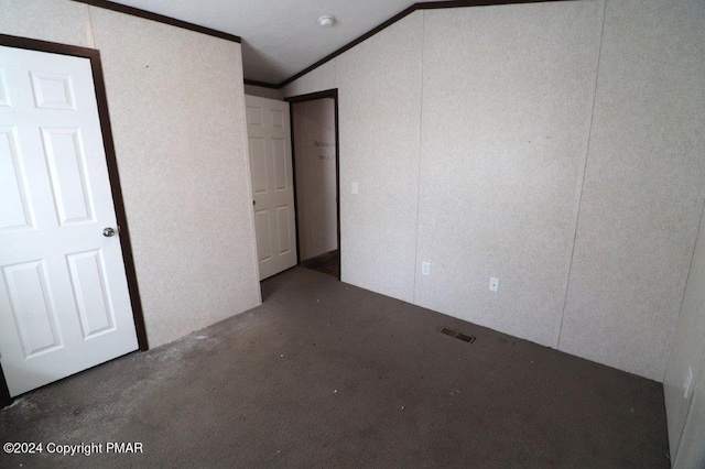 unfurnished bedroom with concrete flooring, lofted ceiling, visible vents, and ornamental molding