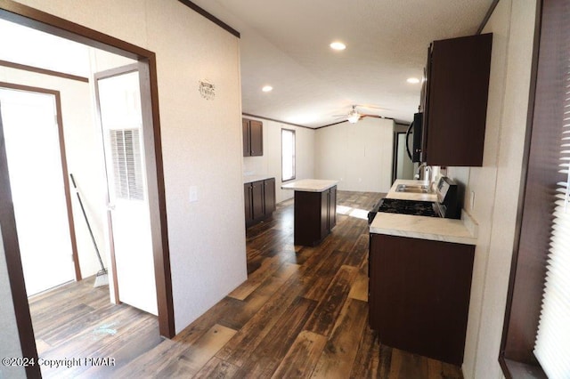 kitchen with dark brown cabinets, vaulted ceiling, light countertops, and dark wood-type flooring