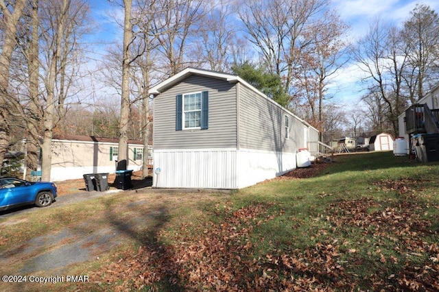 view of side of home with a lawn and an outdoor structure