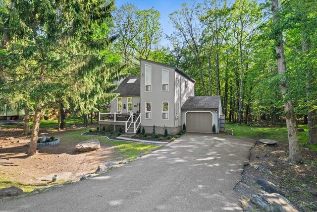 1237 Brentwood Dr, East Stroudsburg, PA 18301 - view of front facade with asphalt driveway, a garage, a deck, and view of scattered trees
