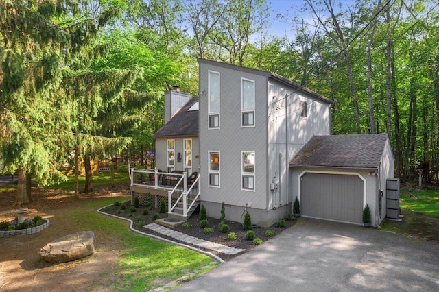 1237 Brentwood Dr, East Stroudsburg, PA 18301 - view of front of house featuring asphalt driveway, a garage, a chimney, a wooden deck, and roof with shingles