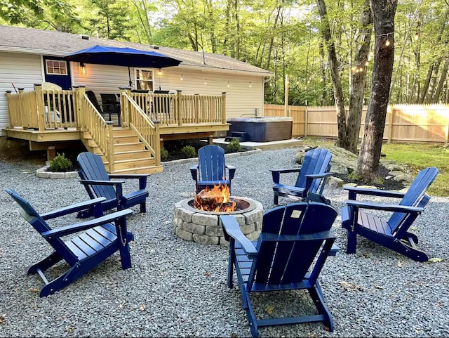 view of patio / terrace with stairway, a wooden deck, fence private yard, an outdoor fire pit, and a hot tub