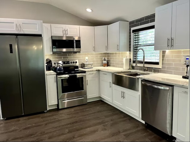 kitchen featuring white cabinets, vaulted ceiling, stainless steel appliances, and a sink