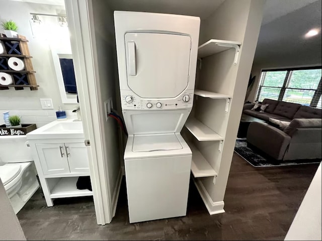 laundry room with stacked washer and clothes dryer, a sink, and laundry area
