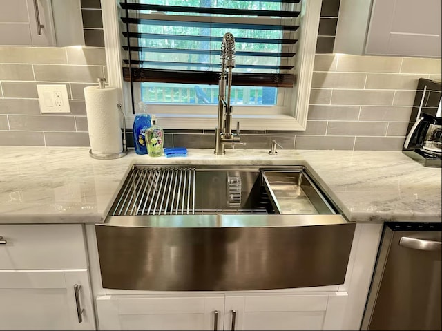 details featuring light stone counters, decorative backsplash, white cabinetry, and a sink