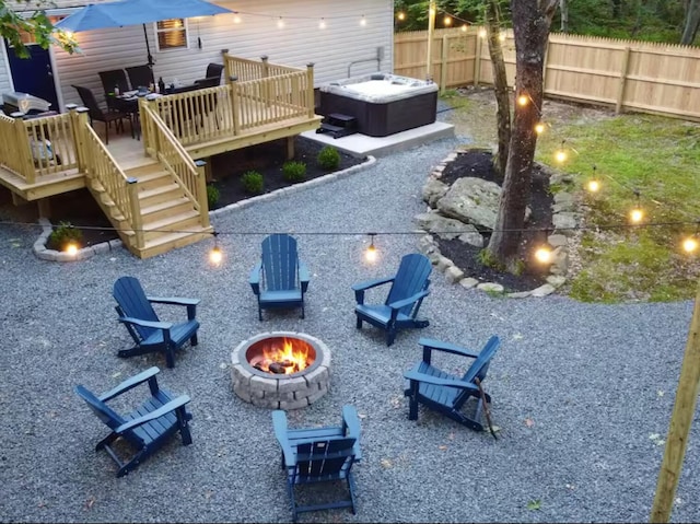 exterior space with a jacuzzi, a fire pit, fence, a wooden deck, and stairs