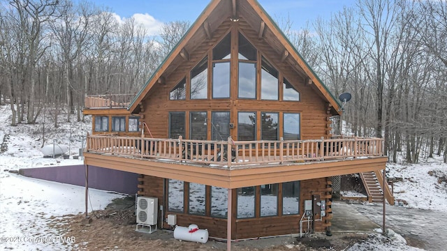 snow covered property featuring a wooden deck and ac unit