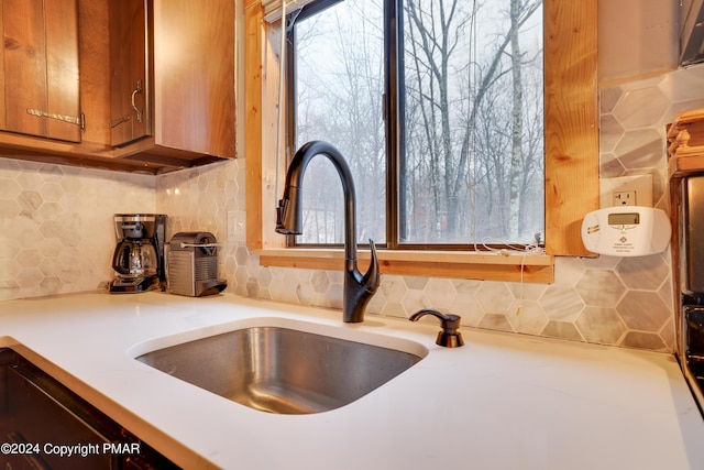 interior details featuring brown cabinets, decorative backsplash, a sink, and light countertops