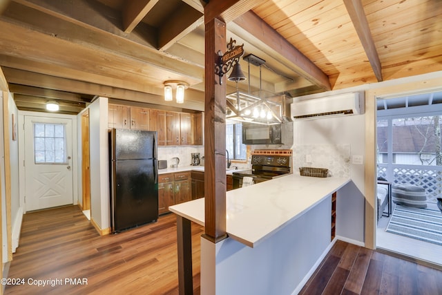 kitchen with black appliances, a peninsula, a wealth of natural light, and a wall mounted air conditioner