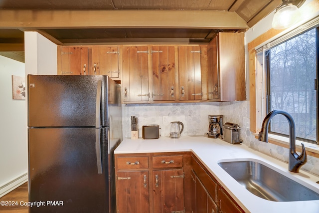 kitchen featuring brown cabinetry, baseboard heating, a sink, and freestanding refrigerator