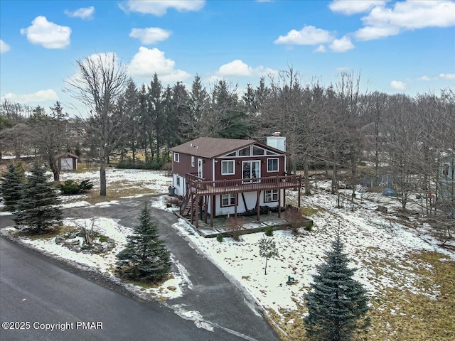 view of front of home with dirt driveway, stairway, a chimney, a deck, and a patio area