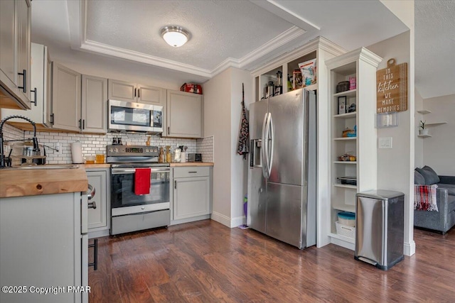 kitchen featuring stainless steel appliances, wooden counters, dark wood-style floors, a sink, and backsplash