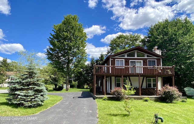 view of front of house featuring a deck, a front lawn, a chimney, and stucco siding