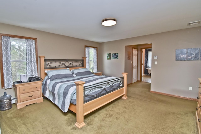 carpeted bedroom featuring a baseboard radiator, baseboards, and visible vents