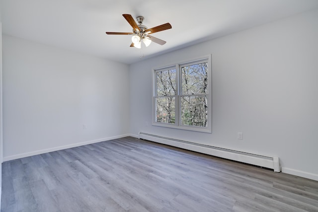 empty room featuring wood finished floors, baseboards, ceiling fan, and a baseboard heating unit