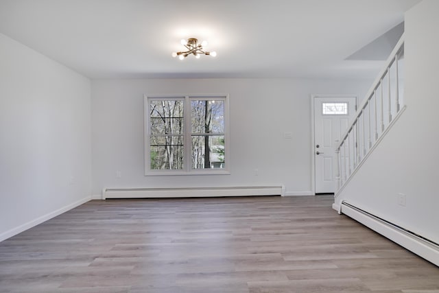 unfurnished living room with baseboards, a baseboard radiator, stairs, and a notable chandelier